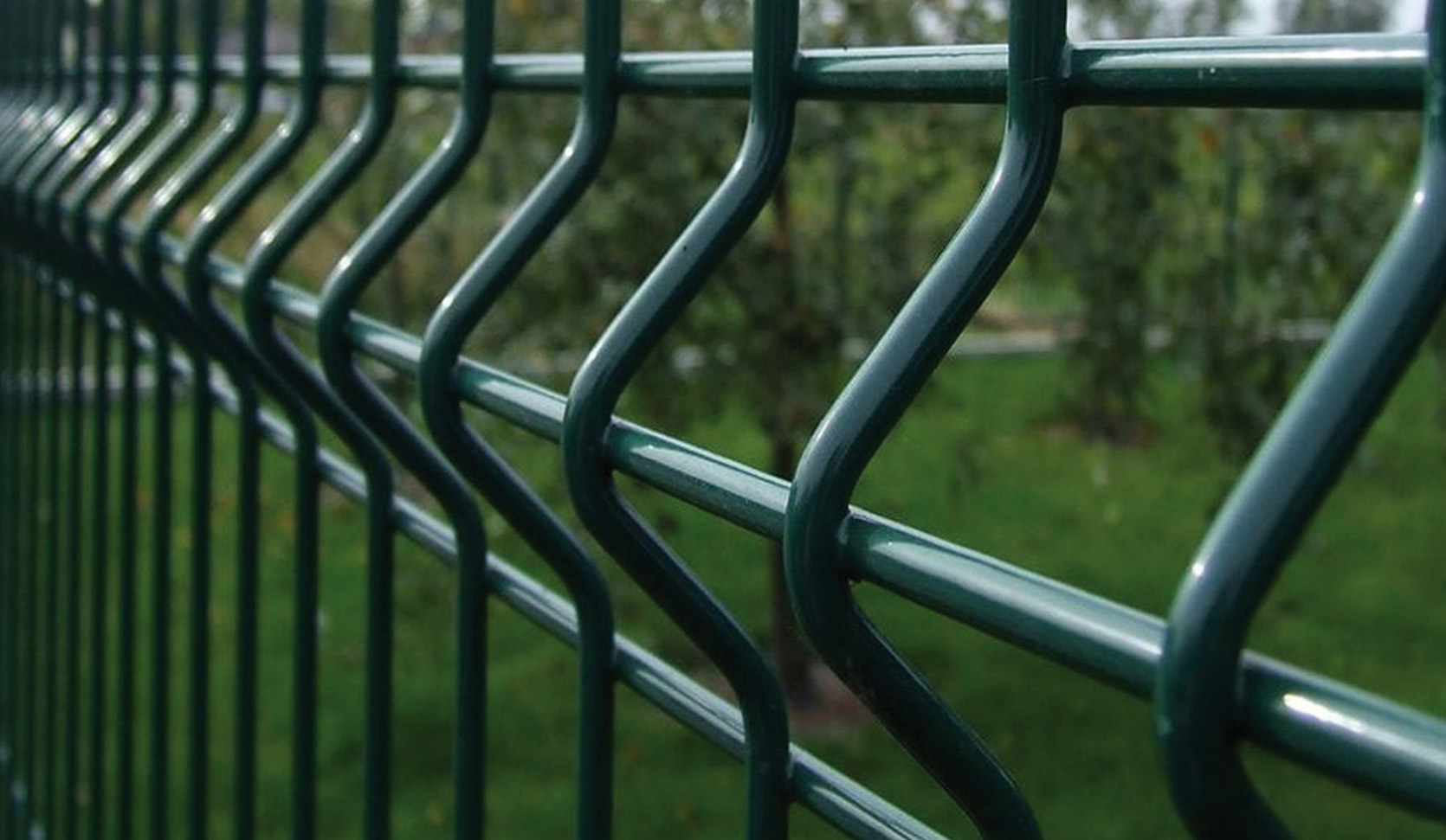 Green V-fold welded mesh fence panels along a path